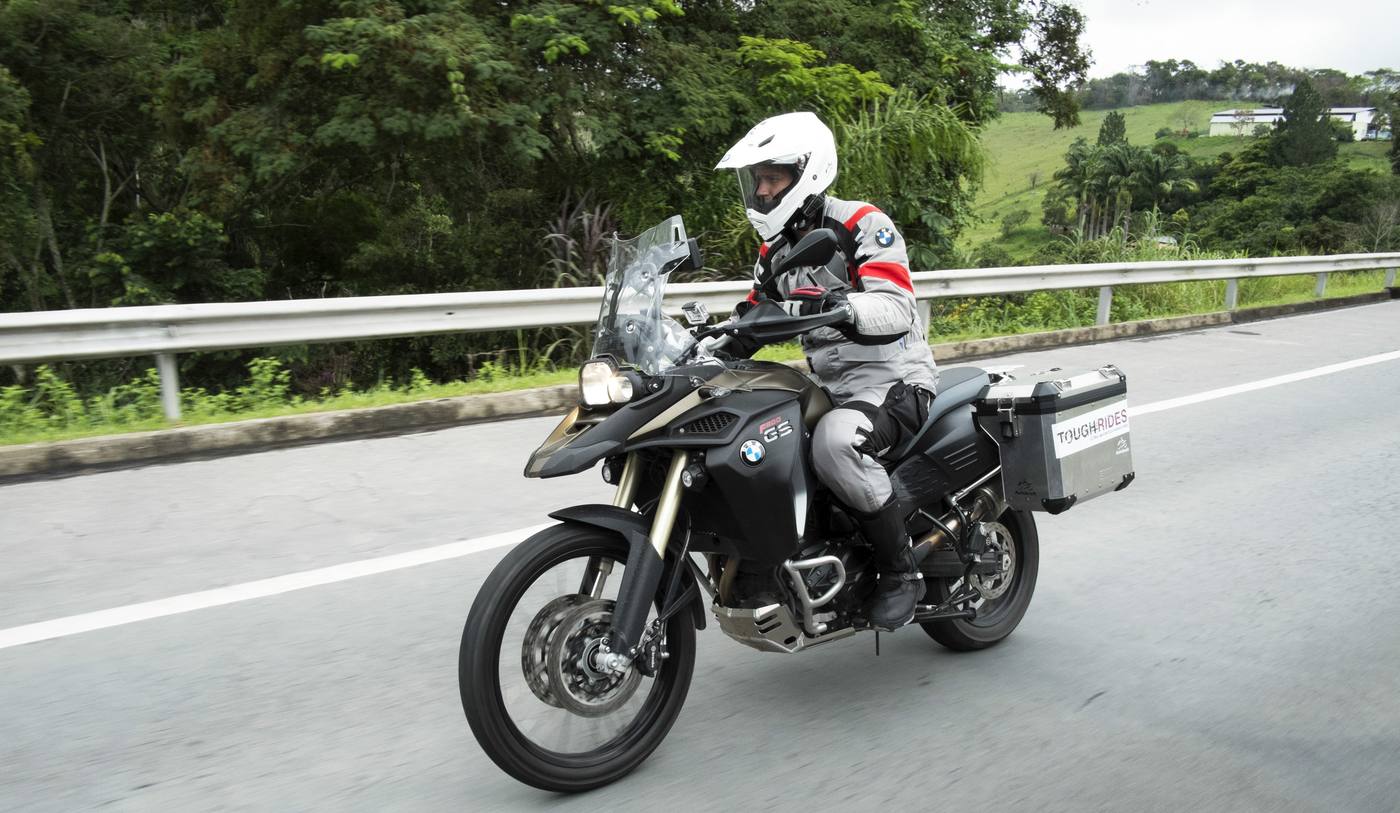 Ryan Pyle riding a BMW motorcycle on a road in Brazil