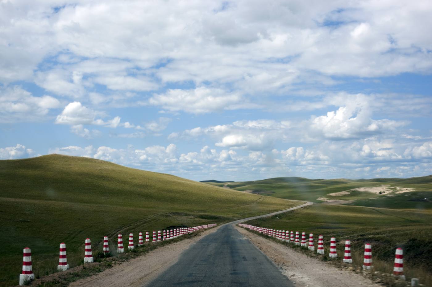 An empty road running through green grassland in China