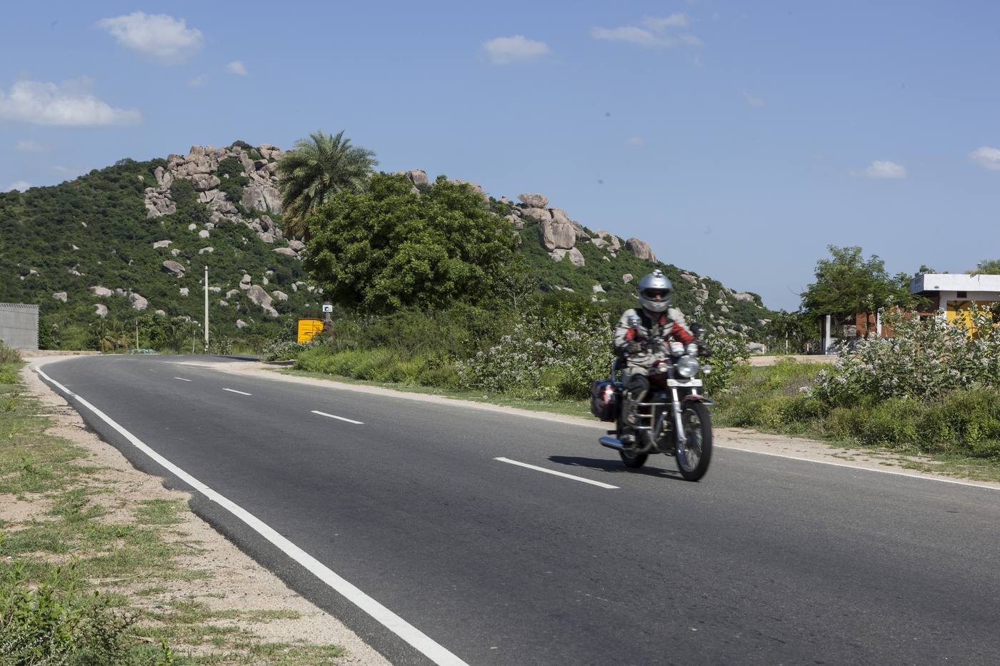 A motorcyclist riding along an open road in southern India